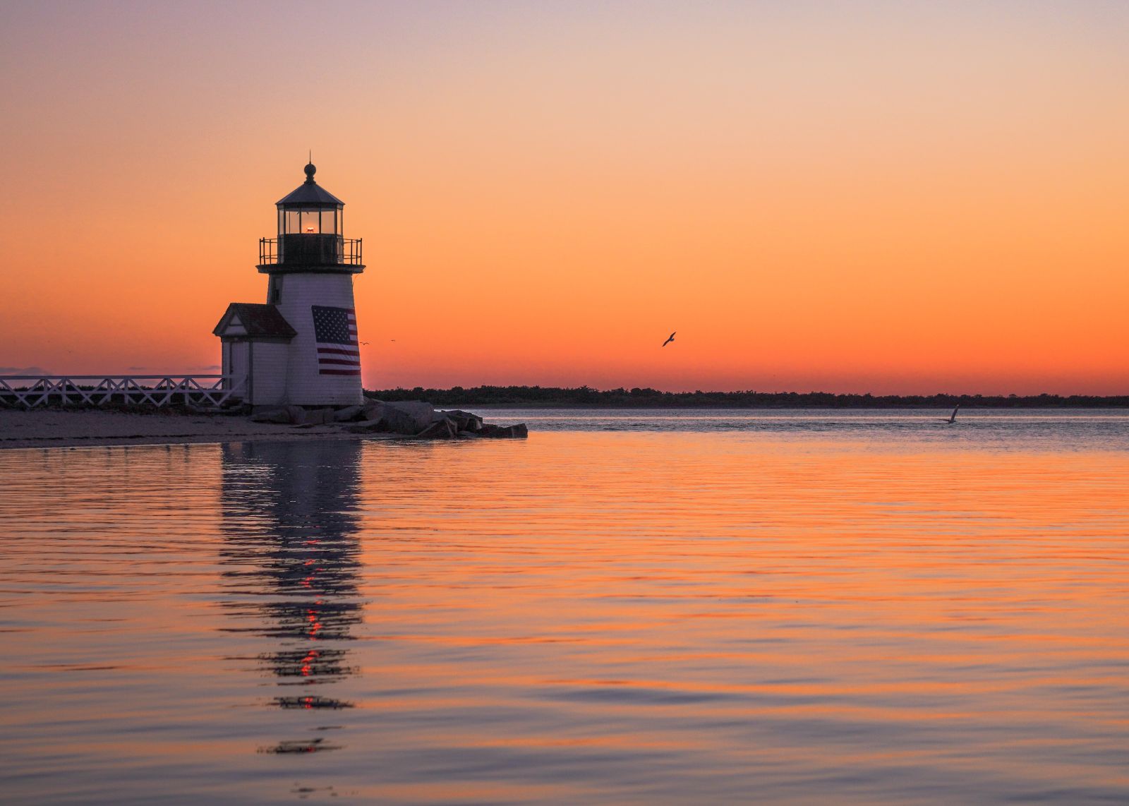 Lighthouse out at sea with sunset hues  