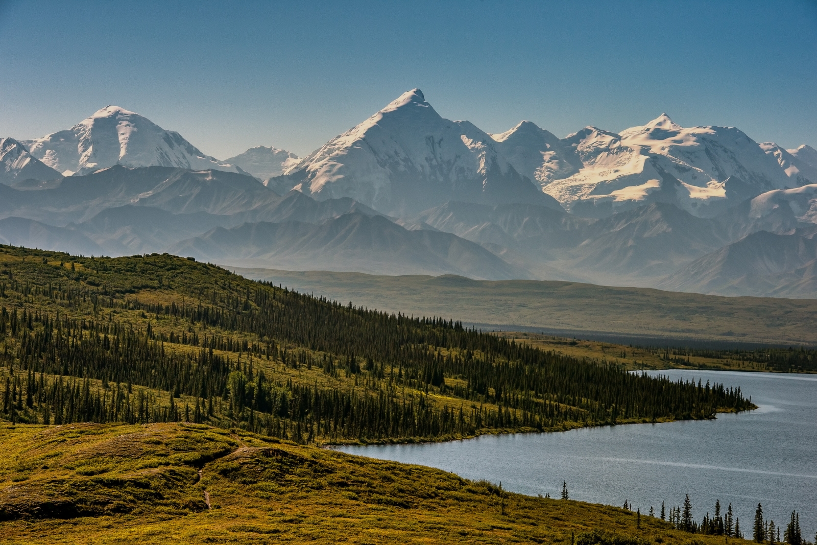 Large mountains with green, forested land in the foreground