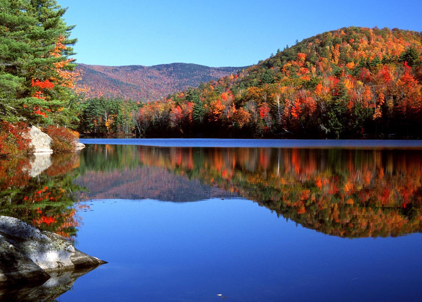 Reflections of fall colours on a still lake in New Hampshire, USA