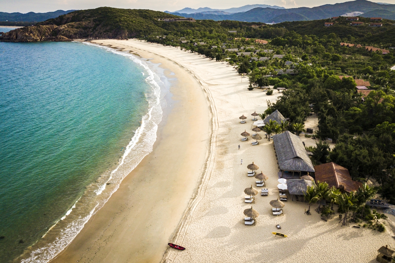 Aerial shot of the sand beach with sun loungers and parasols at luxury resort Zannier Bai San Ho in Vietnam