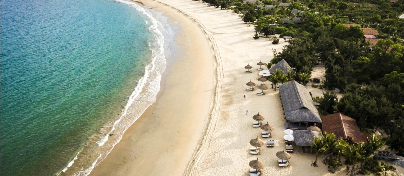 Aerial shot of the sand beach with sun loungers and parasols at luxury resort Zannier Bai San Ho in Vietnam