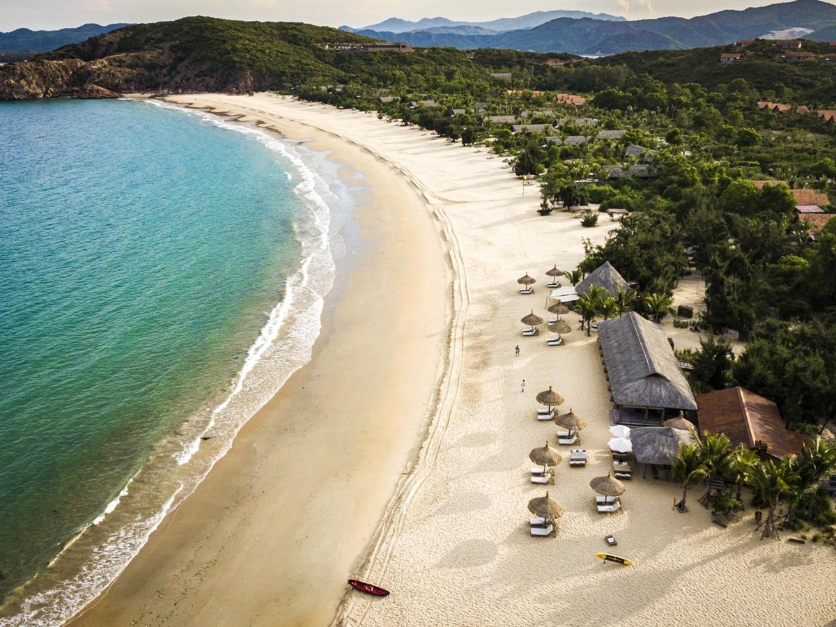 Aerial shot of the sand beach with sun loungers and parasols at luxury resort Zannier Bai San Ho in Vietnam