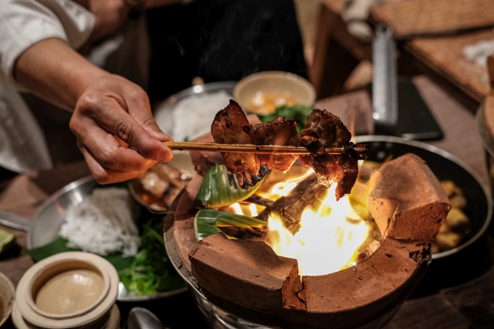 Chef cooking over a traditional oven at luxury resort Zannier Bai San Ho in Vietnam