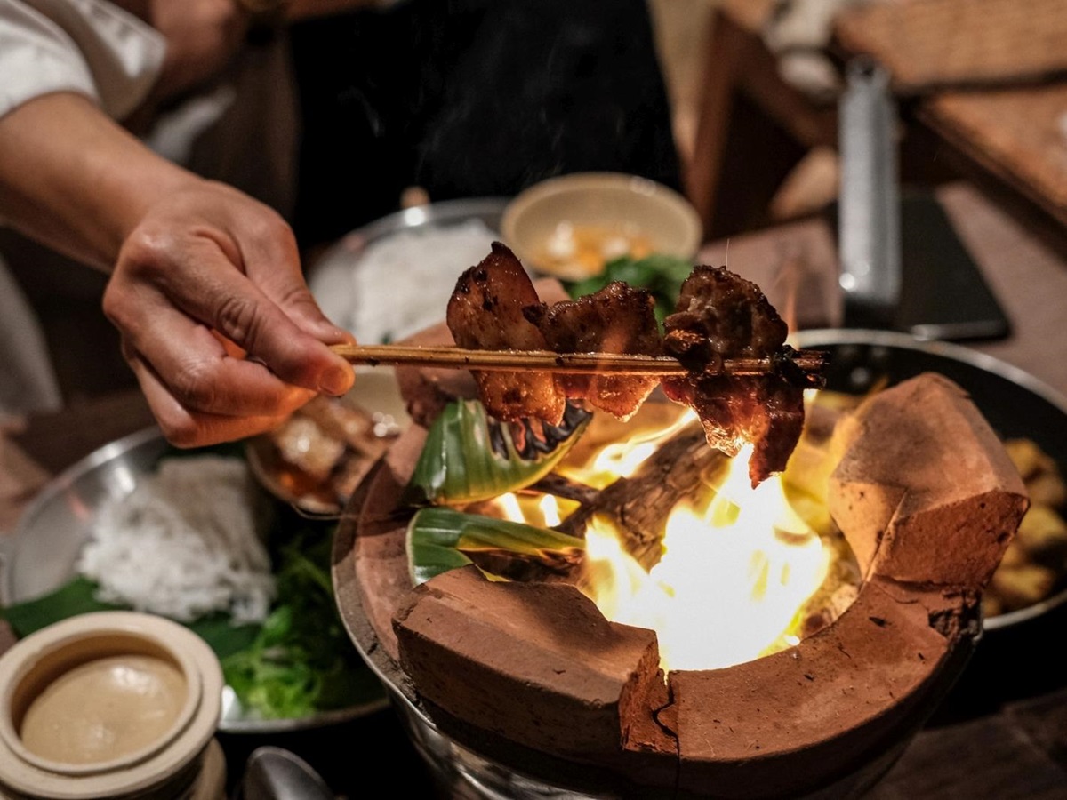Chef cooking over a traditional oven at luxury resort Zannier Bai San Ho in Vietnam
