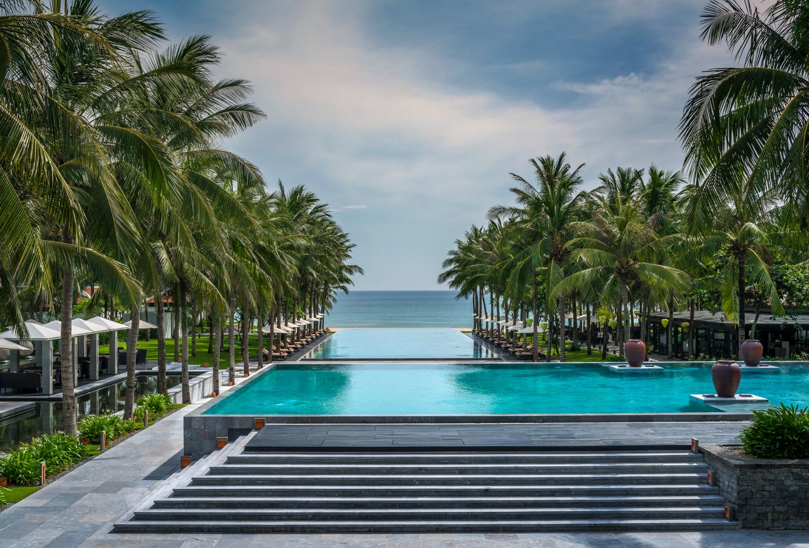 Main pool with coconut trees running down the side at luxury resort Four seasons Nam Hai 