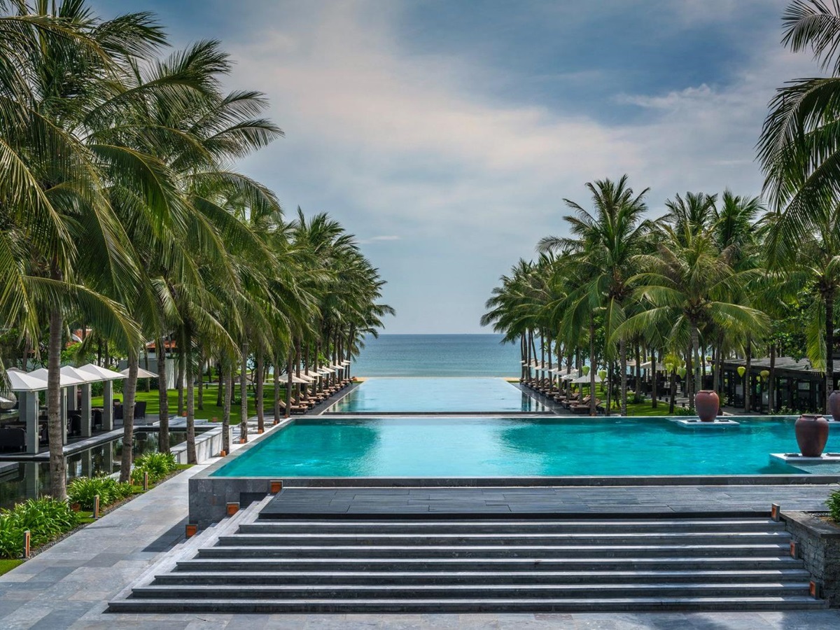 Main pool with coconut trees running down the side at luxury resort Four seasons Nam Hai