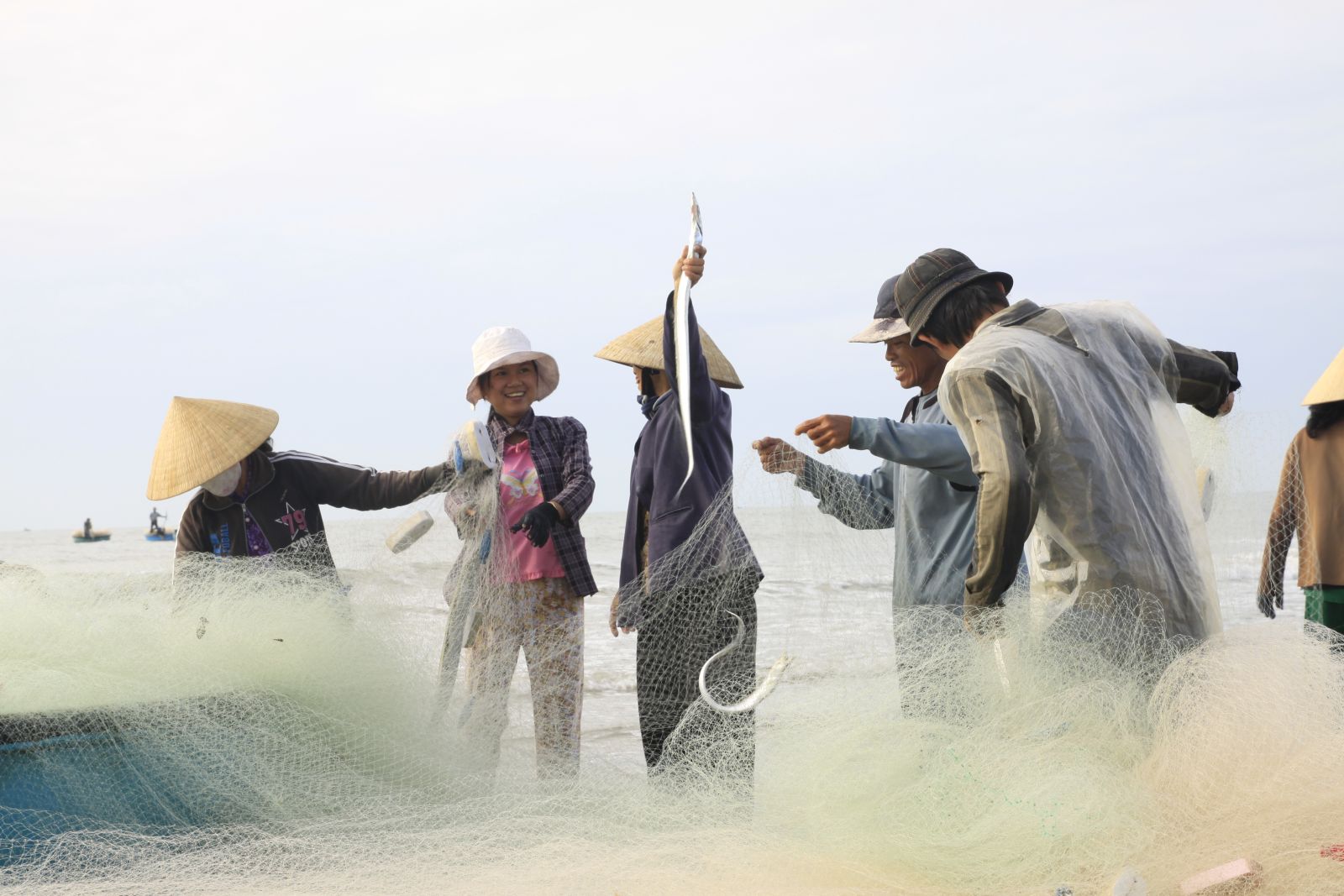 Local people bringing in fresh fish and fishing nets on the Vietnamese coast