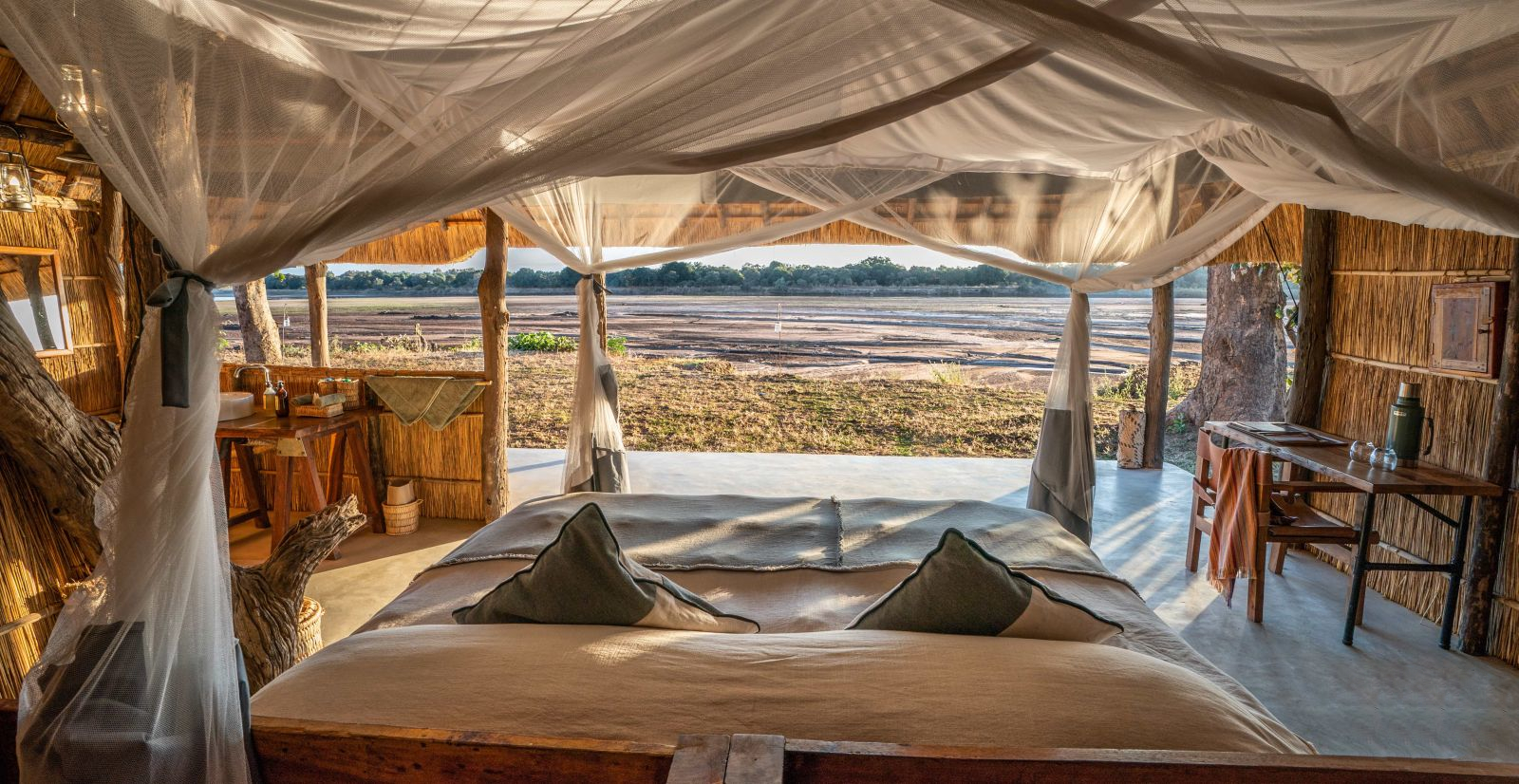 View from a chalet with ensuite bathroom and private terrace over the dried river bed at luxury safari camp Kakuli Bush Camp in Zambia's South Luangwa National Park