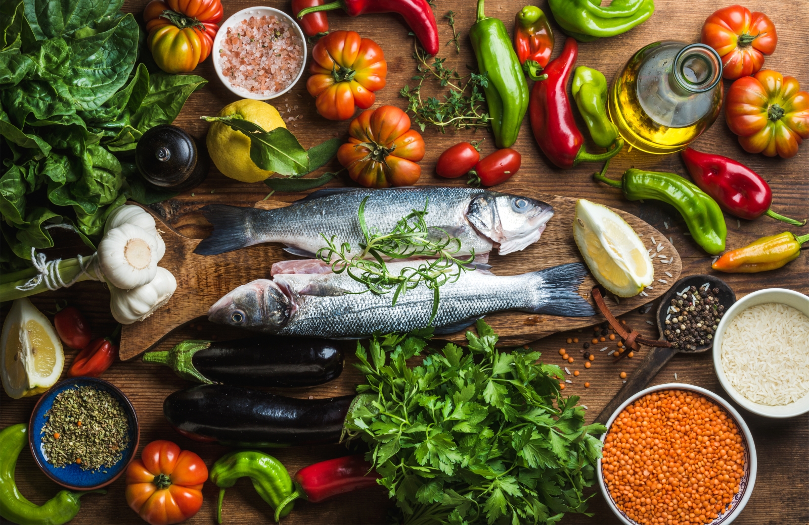 Freshly-caught fish surrounded by fresh vergetables and herbs
