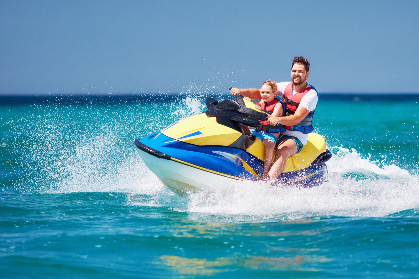 Father and sun jetskiing in turquoise waters