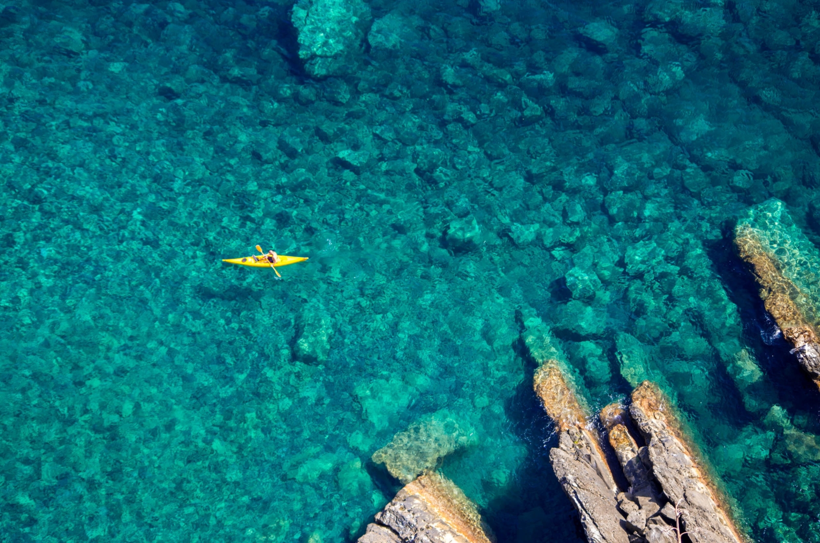 Aerial shot of a man kayaking in turquoise waters
