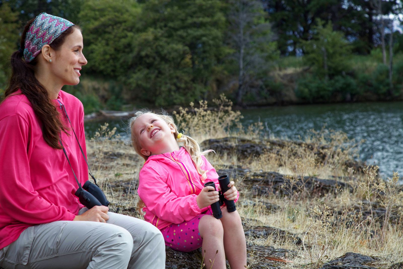 A mother and daughter wildlife watching by a lake