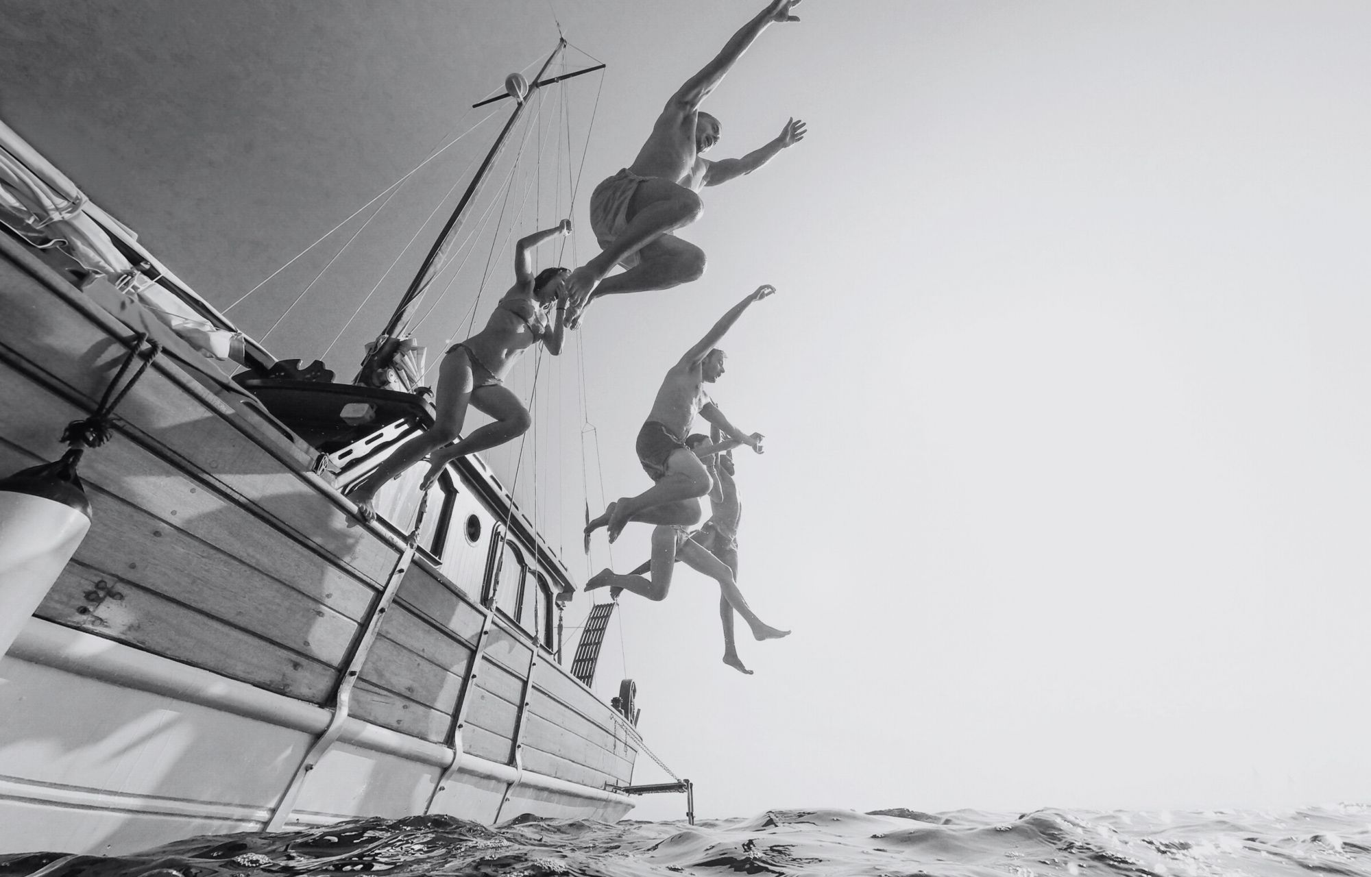 People jumping nto the sea from the side of a boat