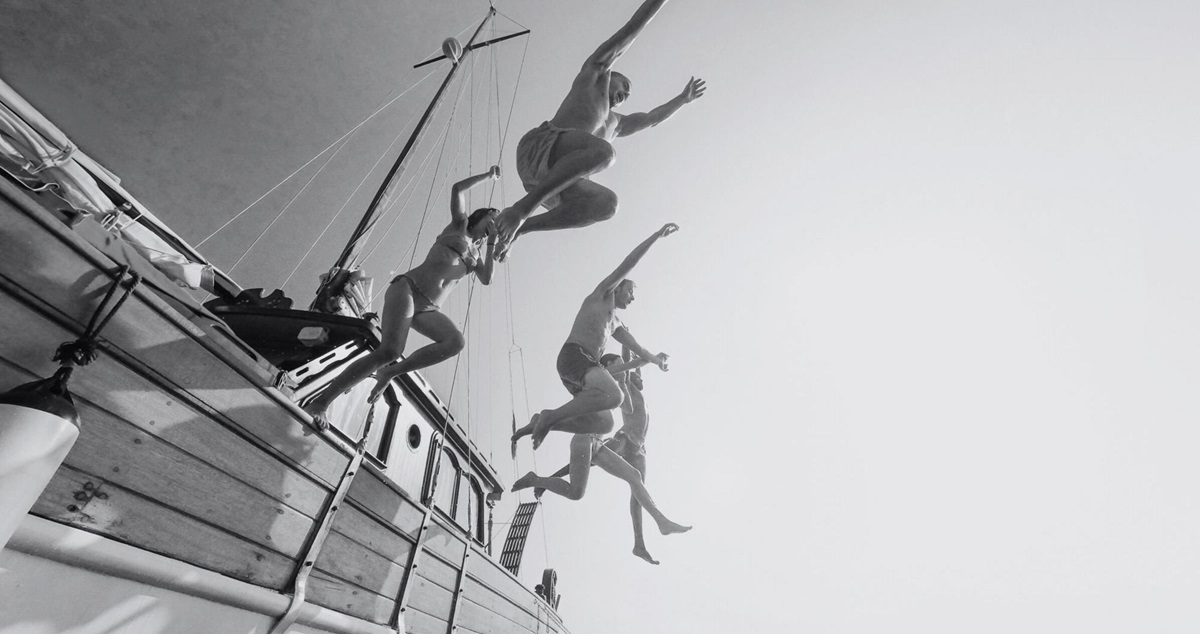 People jumping nto the sea from the side of a boat