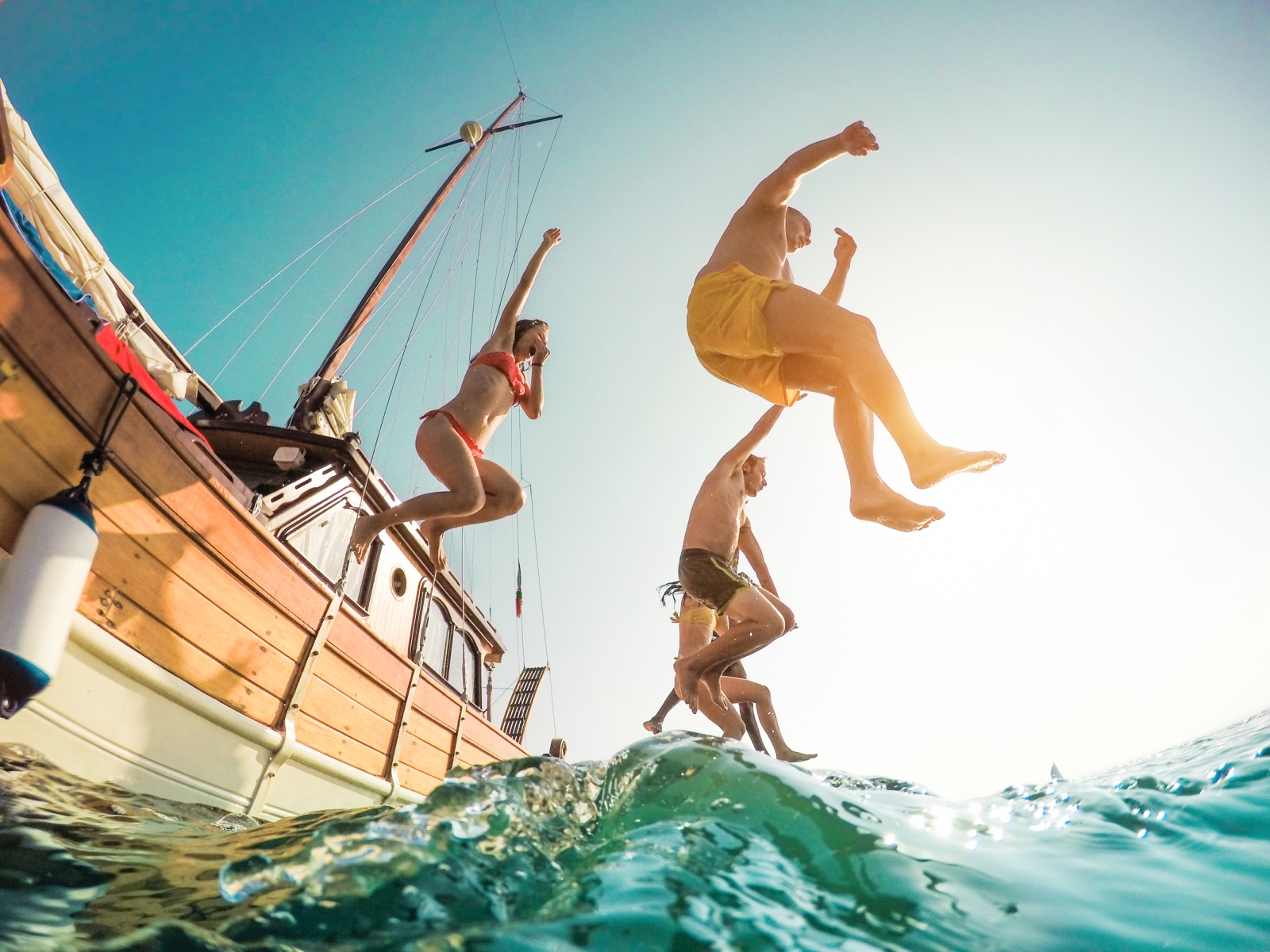 Friends jumping off a sailing boat