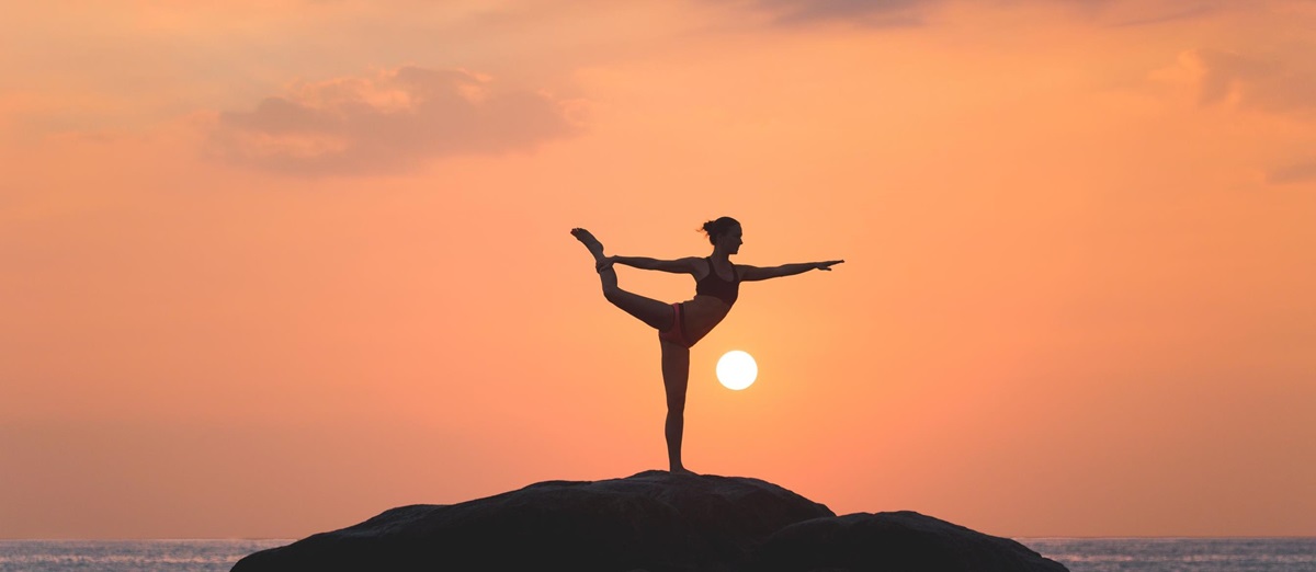 A lady doing the warrior yoga position in the sunset