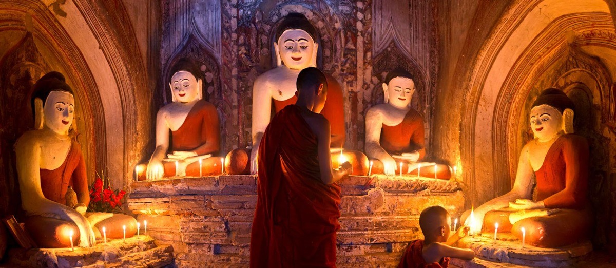 Young Buddhist monks lighting candles in a temple