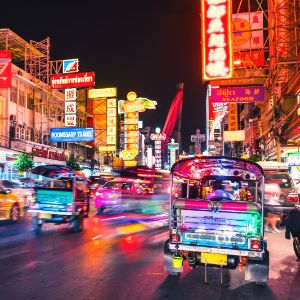 Tuk-tuks driving through the streets of Bangkok at night