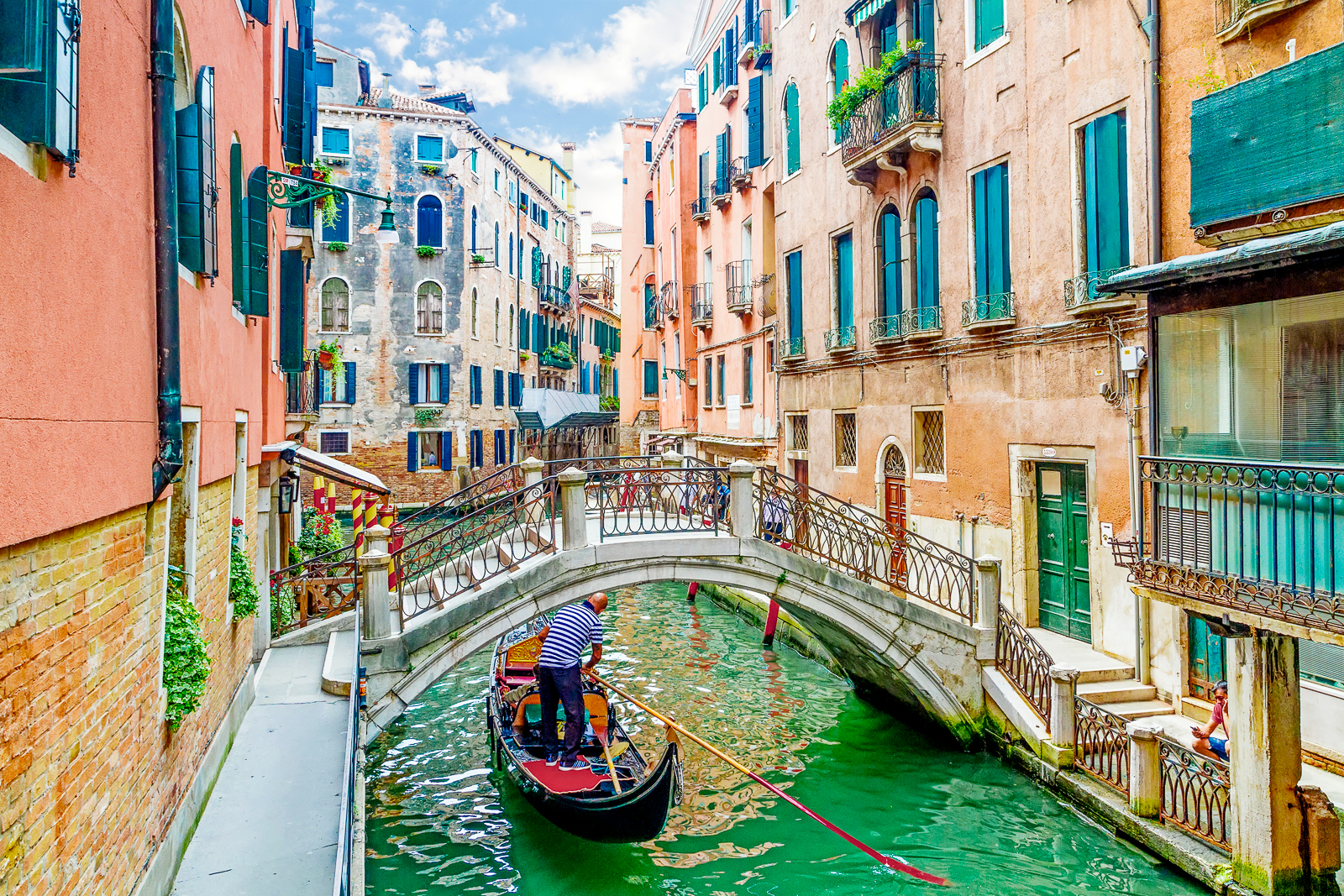 A man rowing a gondola along a Venetian canal