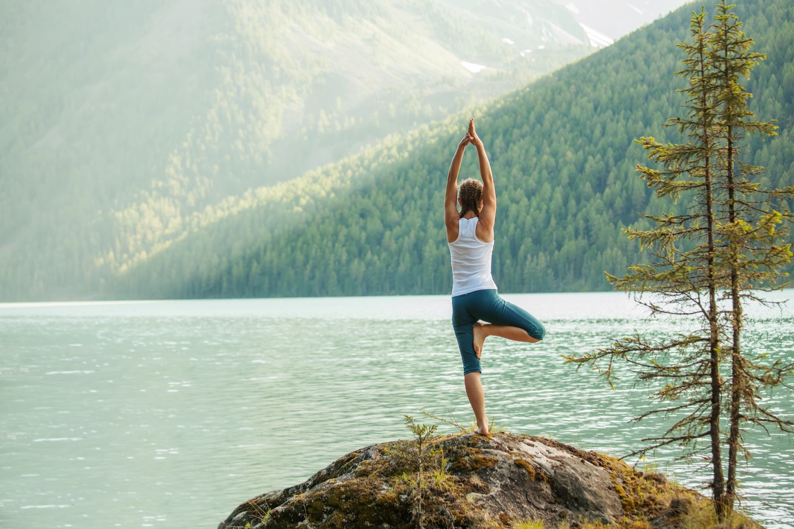 A woman practicing yoga overlooking a mountain lake