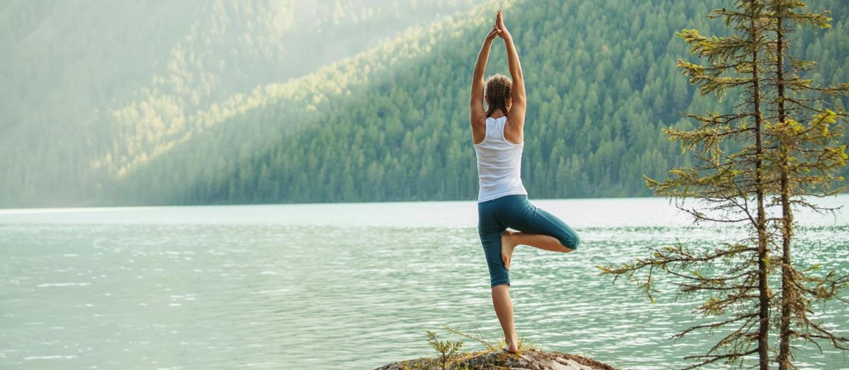 A woman practicing yoga overlooking a mountain lake