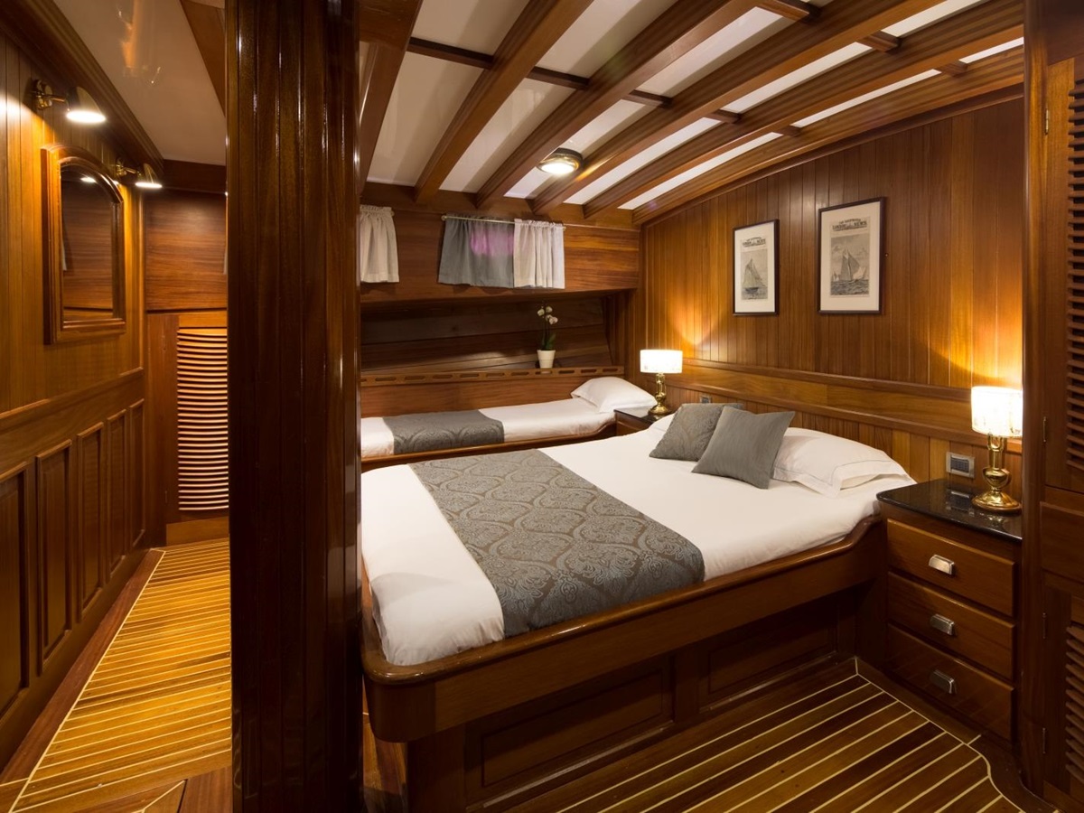 Family cabin with double bed and single bed, storage and wooden decor onboard the luxury gulet Carpe Diem 7