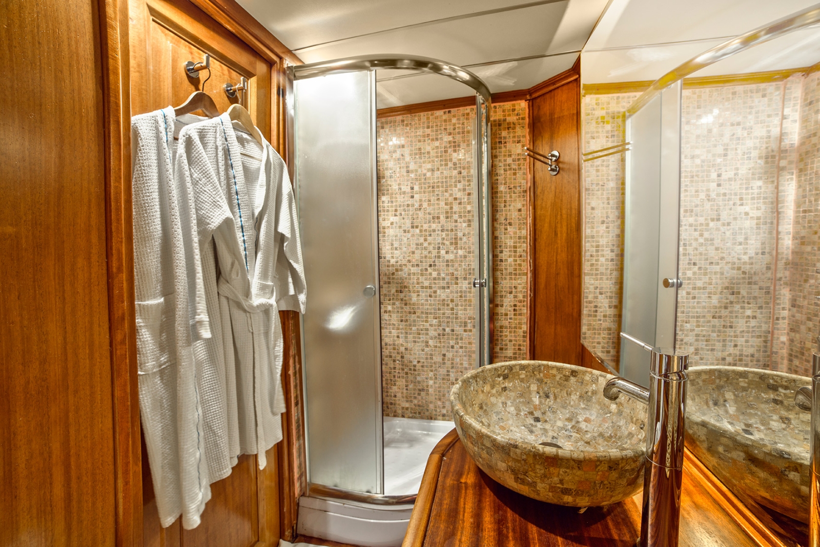 Bathroom with wooden features and mosaic tile walls, with shower and single vanity onboard the luxury gulet Dea Del Mare