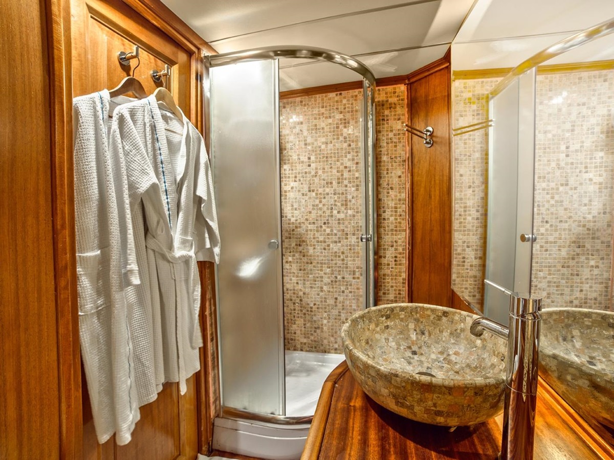 Bathroom with wooden features and mosaic tile walls, with shower and single vanity onboard the luxury gulet Dea Del Mare