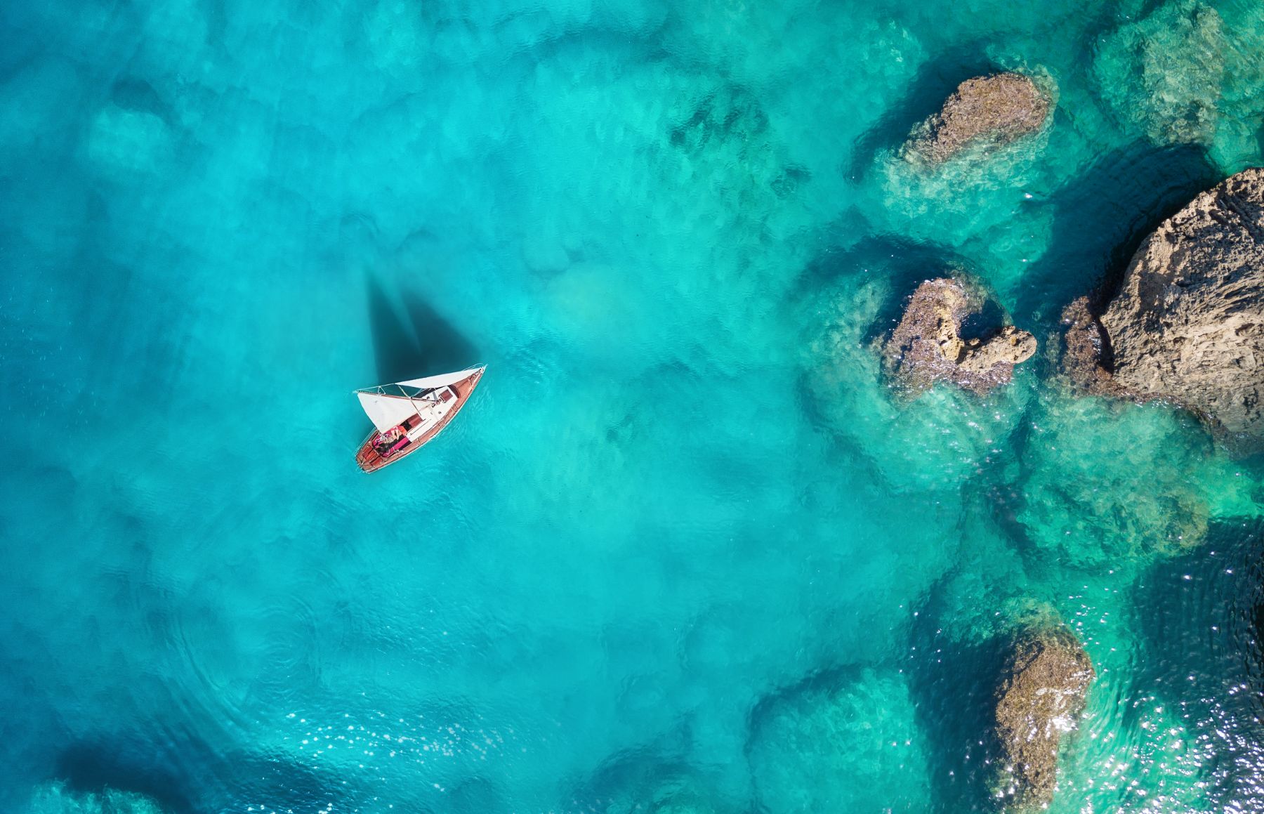 Aerial view of a yacht sailing through turquoise waters