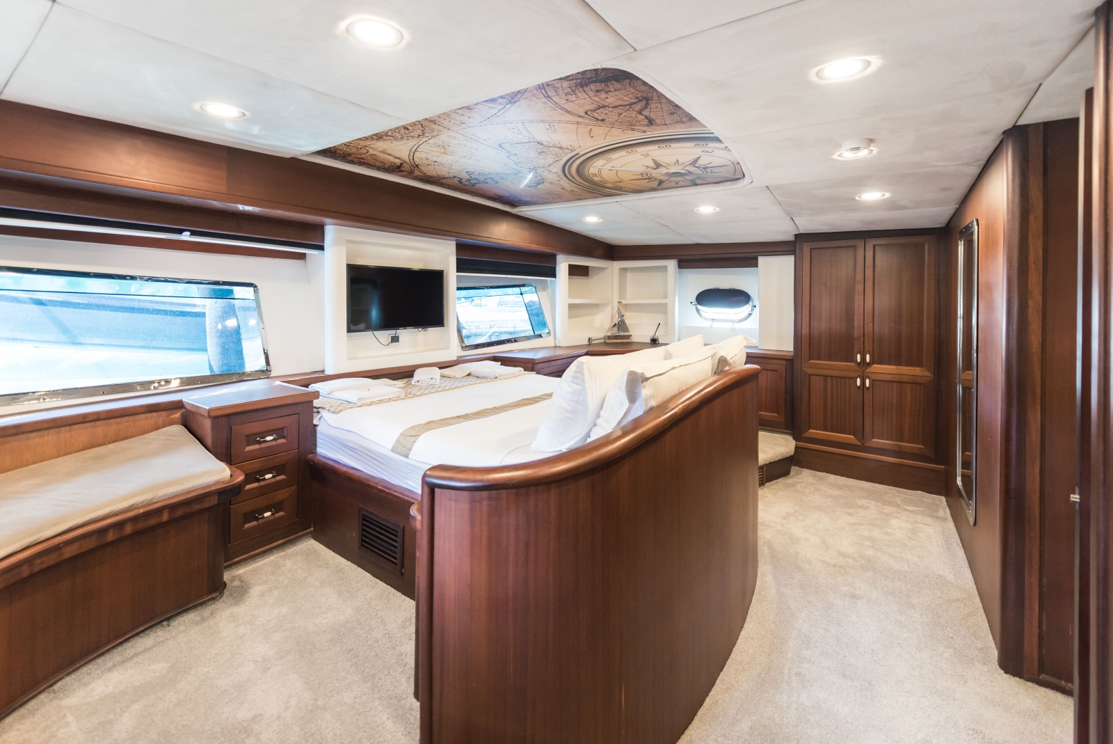 Master bedroom onboard the the luxury gulet Virtuoso with big windows, a flat screen tv and plenty of storage