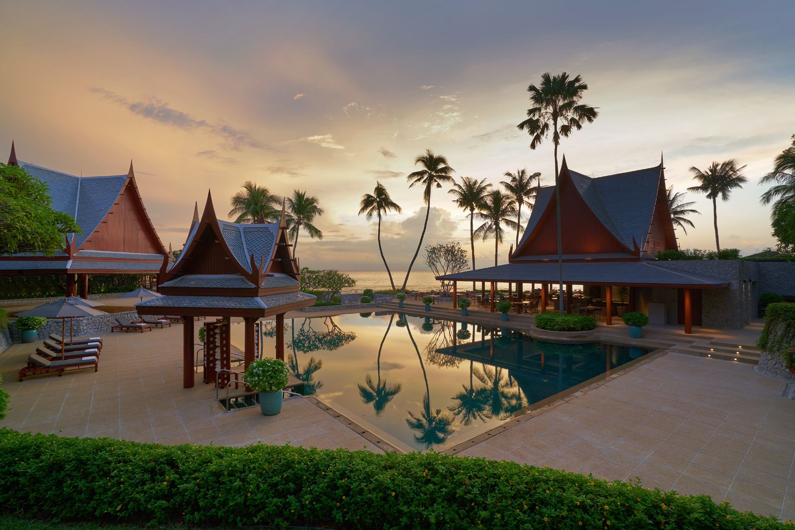 Outdoor pool area surrounded pavilions and palm trees at Luxury resort Chiva Som