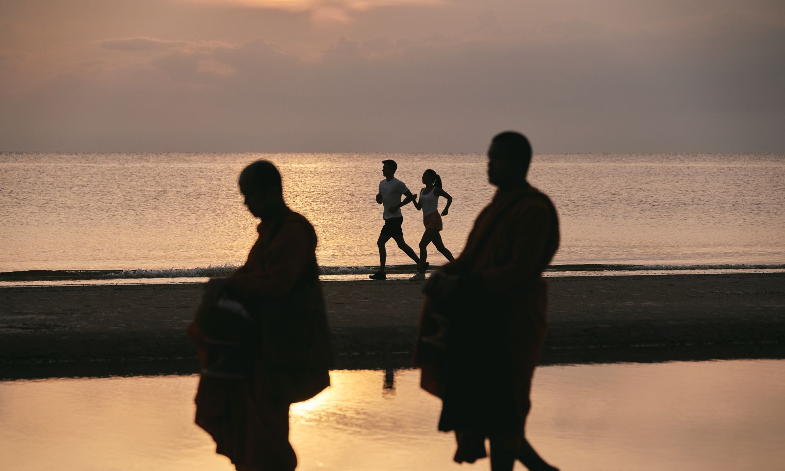 Couple running on the beach at sunrise 